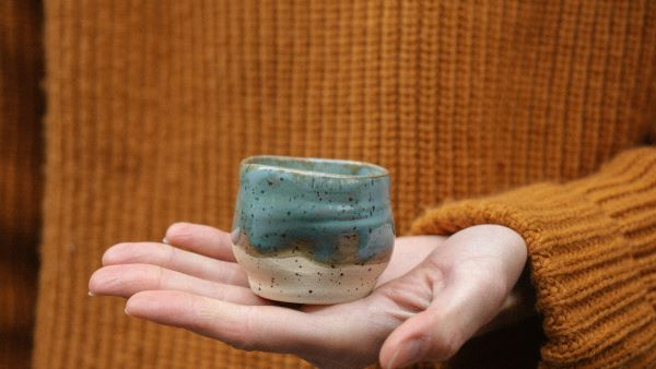 Main tenant un pot en céramique artisanale, symbole d’une déco éthique et durable